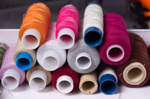 Various multicolored used sewing threads in a box, stacked in a pile Stock Photos