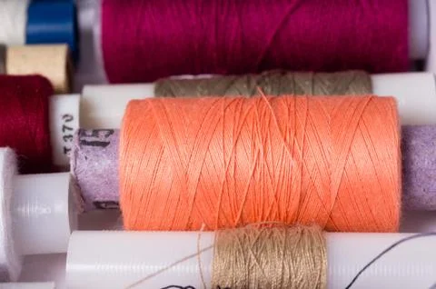Various multicolored used sewing threads in a box, stacked in a row Stock Photos