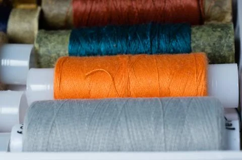 Various multicolored used sewing threads in a box, stacked in a row Stock Photos