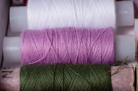 Various multicolored used sewing threads in a box, stacked in a row Stock Photos