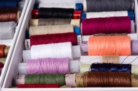 Various multicolored used sewing threads in a box, stacked in a pile Stock Photos