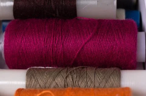 Various multicolored used sewing threads in a box, stacked in a row Stock Photos