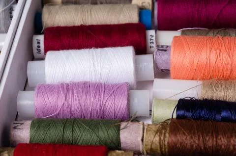 Various multicolored used sewing threads in a box, stacked in a pile Stock Photos