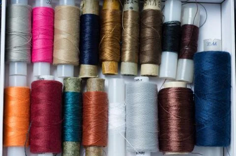 Various multicolored used sewing threads in a box, stacked in a pile Stock Photos