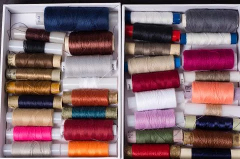 Various multicolored used sewing threads in a box, stacked in a pile Stock Photos