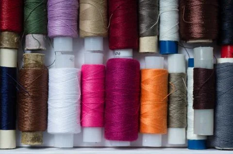 Various multicolored used sewing threads in a box, stacked in a row Stock Photos