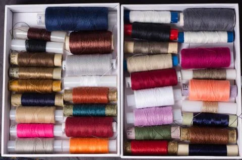 Various multicolored used sewing threads in a box, stacked in a pile Foto stock