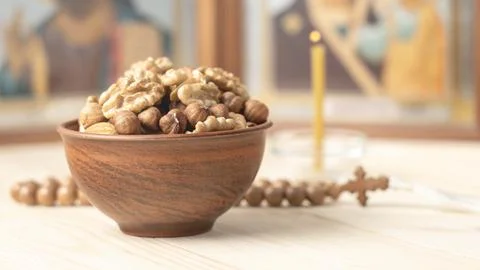Various nuts in clay cup on table in front of Orthodox icon. Food for Christians Stock Photos