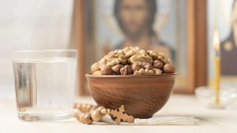 Various nuts in clay cup on table in front of Orthodox icon. Food for Christians Stock Photos