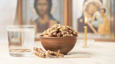 Various nuts in clay cup on table in front of Orthodox icon. Food for Christians Stock Photos