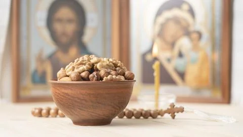 Various nuts in clay cup on table in front of Orthodox icon. Food for Christians Stock Photos