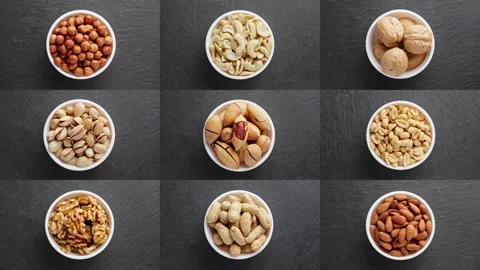 Various nuts rotating at dark background. Different snacks in white bowl. Video stock 293311175