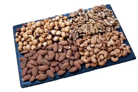 Various nuts sorted on black stone plate isolated on white background. rectan Stock Photos