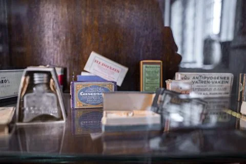 Various objects in boxes on glass shelf at old pharmacy museum in historic town Stock Photos