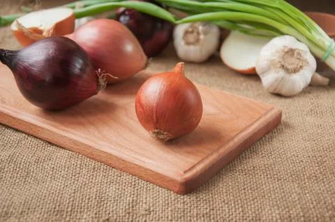 Various onions on a board on a background sacking, burlap Stock Photos