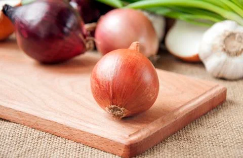 Various onions on a board on a background sacking, burlap Stock Photos