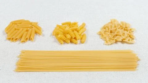 Various pasta on a fabric background. Assorted raw pasta Stock Photos