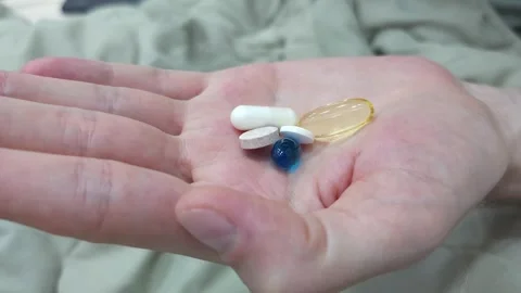 Various pills and supplements held in an open hand. Close-up view of medications Stock Footage 282609887