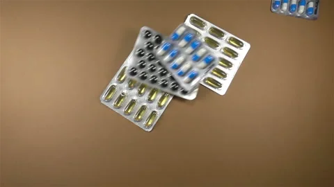 Various pills in blisters falling in slow motion on brown Stock Footage 143174458