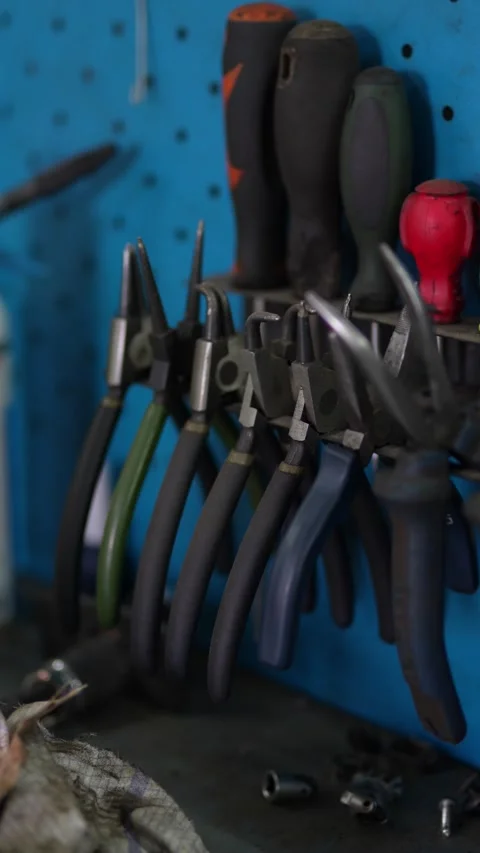 Various pliers and screwdrivers hanging on blue workshop pegboard. Stock Footage 343892443