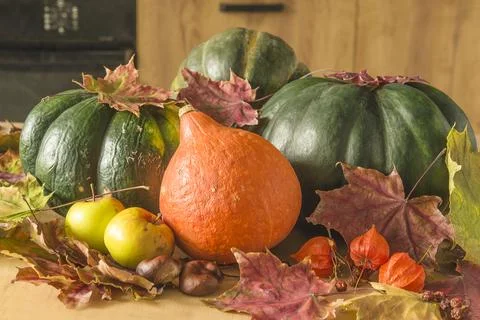 Various pumpinks, apples and dry maple leaves on wooden background Stock Photos