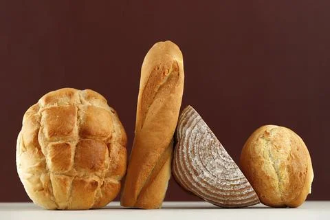 Various Rustic Bread, Sourdough, Baguette, Boule Isolated on Brown Table. Stock Photos