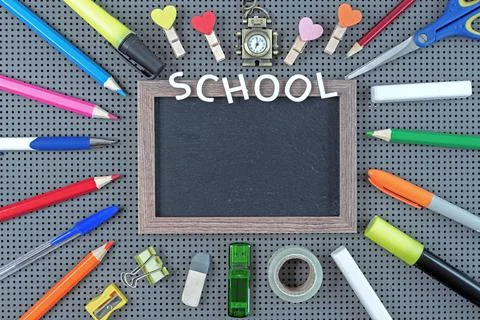 Various school supplies around a black chalk board with a frame. School concept Stock Photos