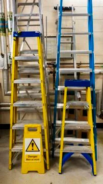 Various sets of ladders in a maintenence workshop Stock Photos
