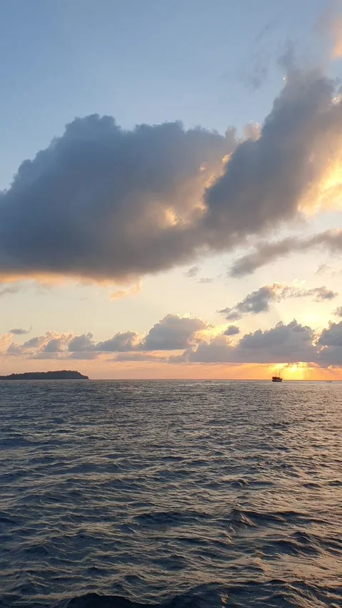 Various shapes of clouds in the sky as the sun rises over the sea Stockbeeldmateriaal 336624818