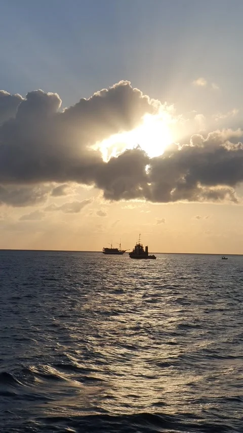 Various shapes of clouds in the sky as the sun rises over the sea Видео 336628969