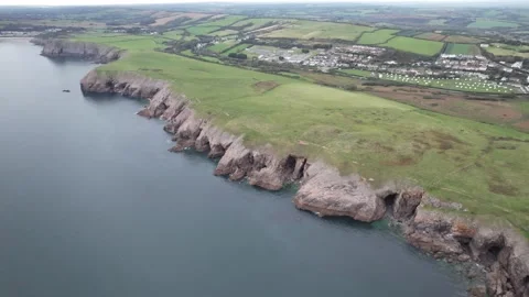 Various shapes of rock formations on shore, village in background Stock Footage 166639688