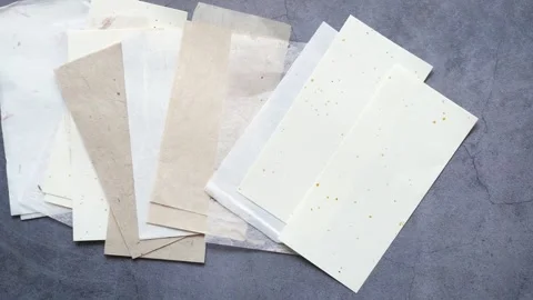 Various sheets of handmade textured paper spread across gray stone backgrou.. Stock-Footage 333260275