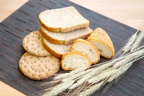 Various sliced bread and wheat on table Stock Photos