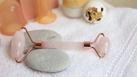 Various spa tools in home bathroom: rose quartz face rolling tool. Stock Footage 148329667