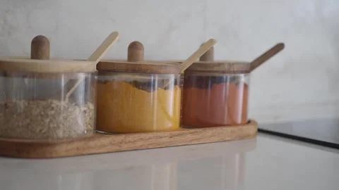 Various spices and herbs in glass jars on a kitchen counter Stock Footage 346194848