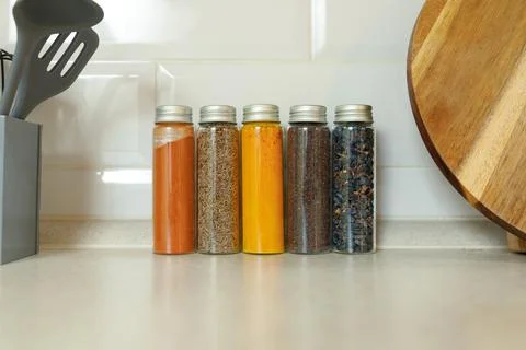 Various spices in jars against the wall on a modern kitchen table with copy Stock Photos