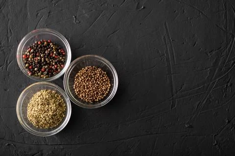 Various spices in three containers. Pepper, coriander, oregano. Dark backgrou Stock Photos
