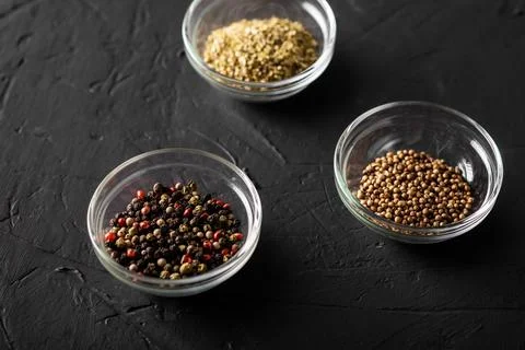 Various spices in three containers. Pepper, coriander, oregano. Dark backgrou Stock Photos