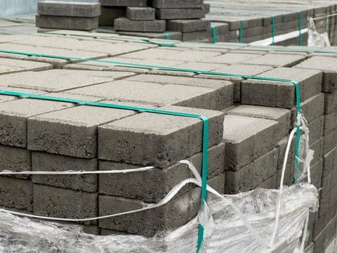 Various stacks of concrete pavement blocks are secured with plastic wrap 库存照片