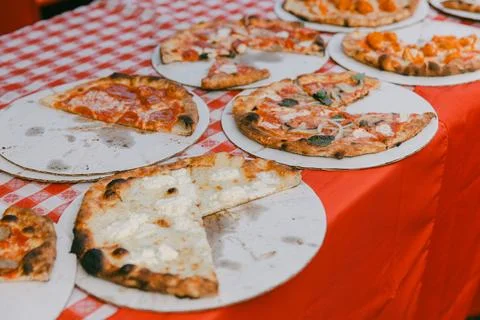 Various styles of pizza displayed on serving boards at a food festival in an Stock Photos