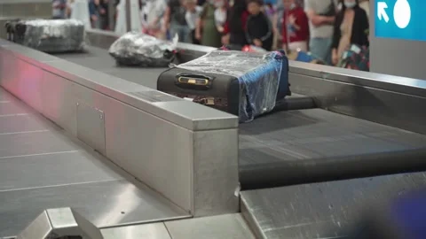 Various suitcases move along a baggage conveyor belt in the arrivals area of the Video stock 160803007