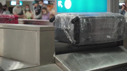 Various suitcases move along a baggage conveyor belt in the arrivals area of the Stock Footage 161140190