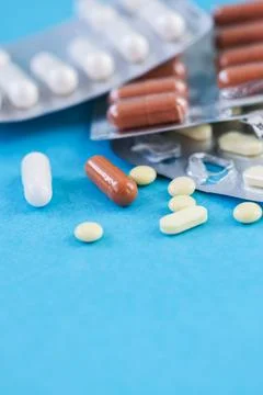 Various tablets, pills on blue background. Stock Photos