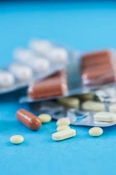 Various tablets, pills on blue background. Stock Photos