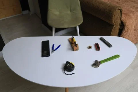 Various tools and repair items laid out on a white table for a DIY project Stock Photos