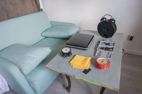Various tools, clocks, and a laptop arranged on a table next to a sofa, Stock Photos