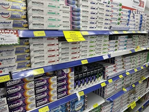 Various toothpaste on the shelves at supermarket Stock Photos