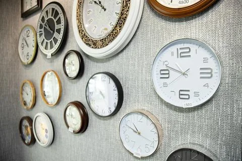 Various types and brands of wall clocks.  Wall clocks hanging on the wall f.. Stock Photos