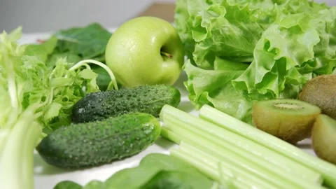 Various types of bright green vegetables and fruits lie on a white table Stock Footage 161868544