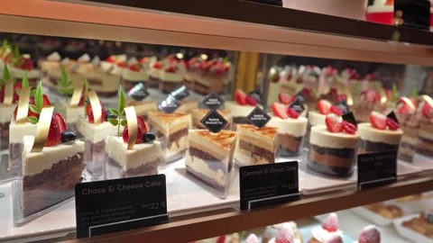 Various types of cakes displayed on the shelf and selling in the bakery shop. Видео 267000935